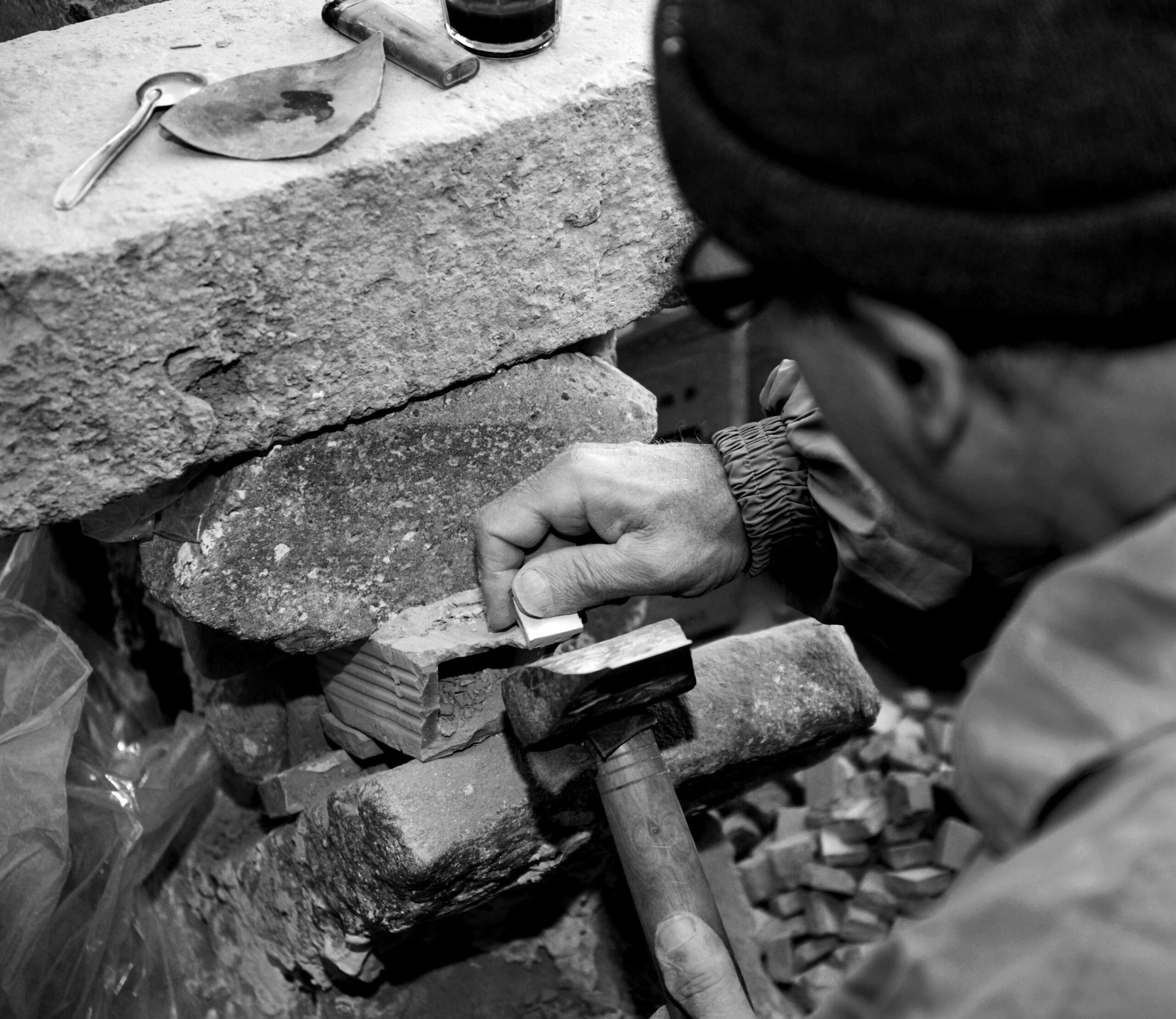 A craftsman in Fès skillfully hammers stone blocks, showcasing traditional methods.